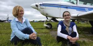 Two ladies sitting beside a small aircraft