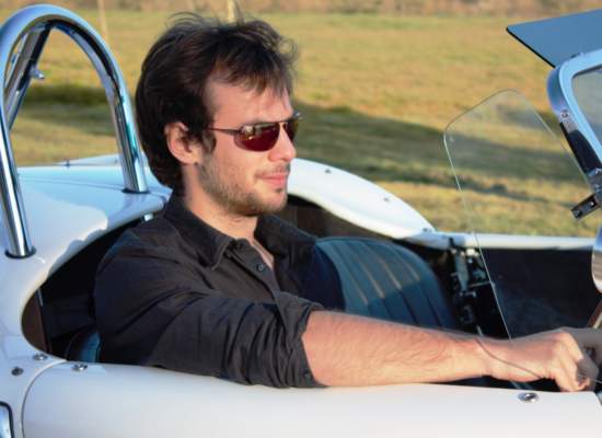 Man in Bigatmo sunglasses and black shirt driving a white A C Cobra