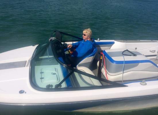 a woman in a blue jacket wearing Bigatmo sunglasses driving a speedboat