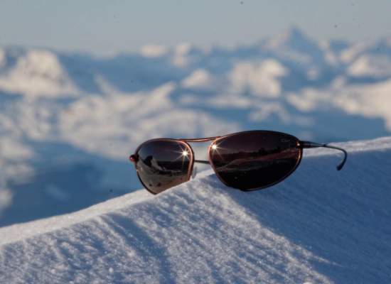 Bigatmo Exo sunglasses balanced on a snow covered ridge in a mountain range.